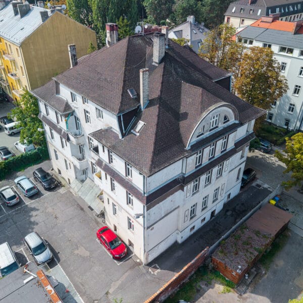 Widok z góry na wielorodzinną kamienicę w Opolu z widocznym dachem i parkingiem